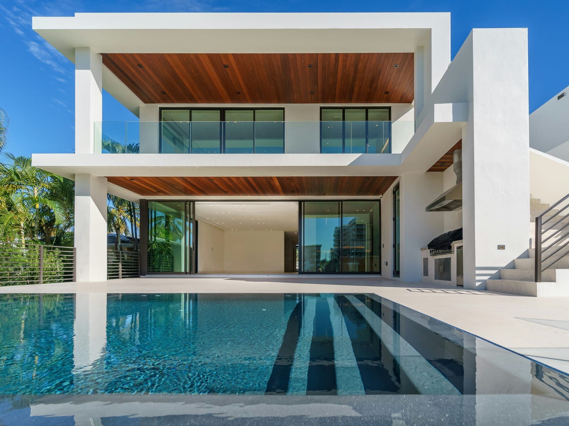 Villa blanca de dos plantas con techos de madera, piscina y grandes ventanales